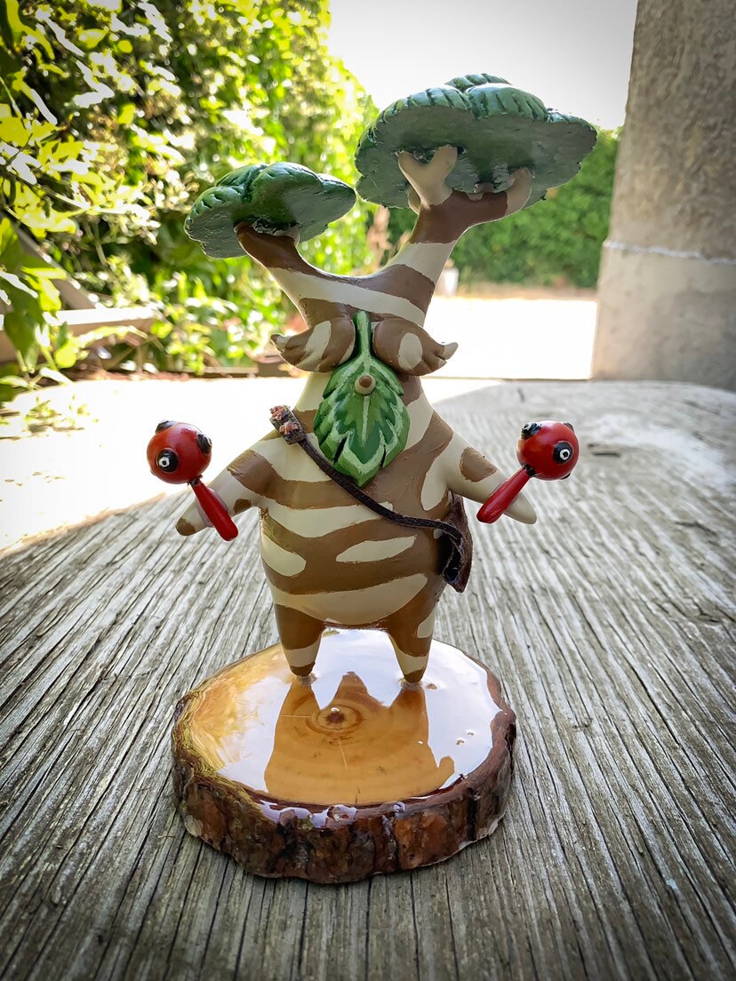 Decorative Hestu figurine on a wooden base outdoors.