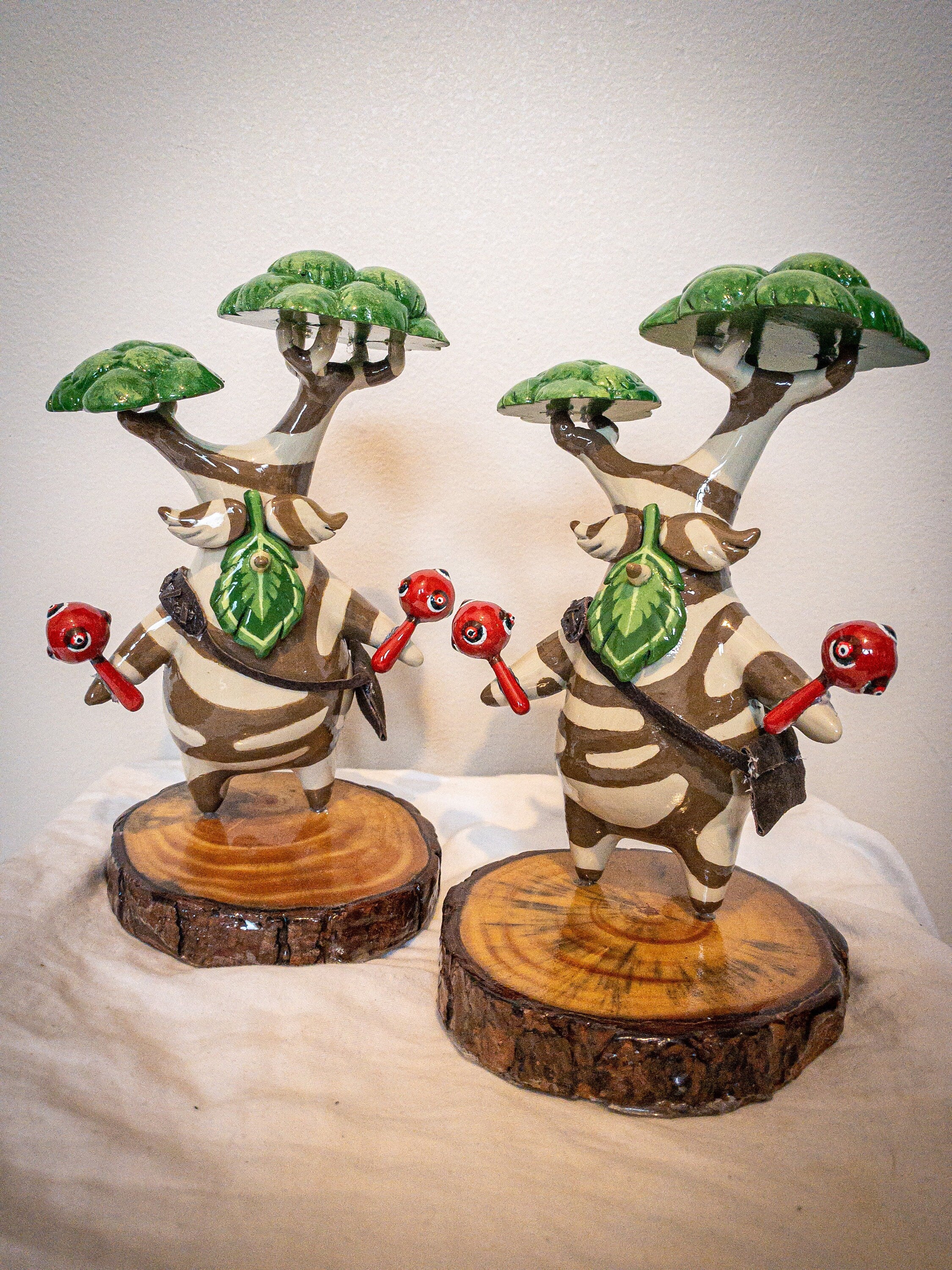 Two decorative figurines with tree-like structures on a neutral background