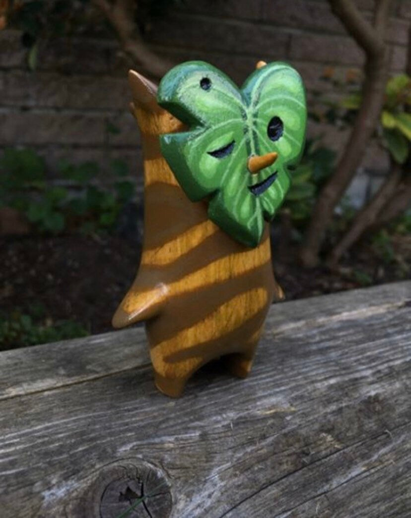 Wooden Korok figure with a leaf-like head on a wooden surface