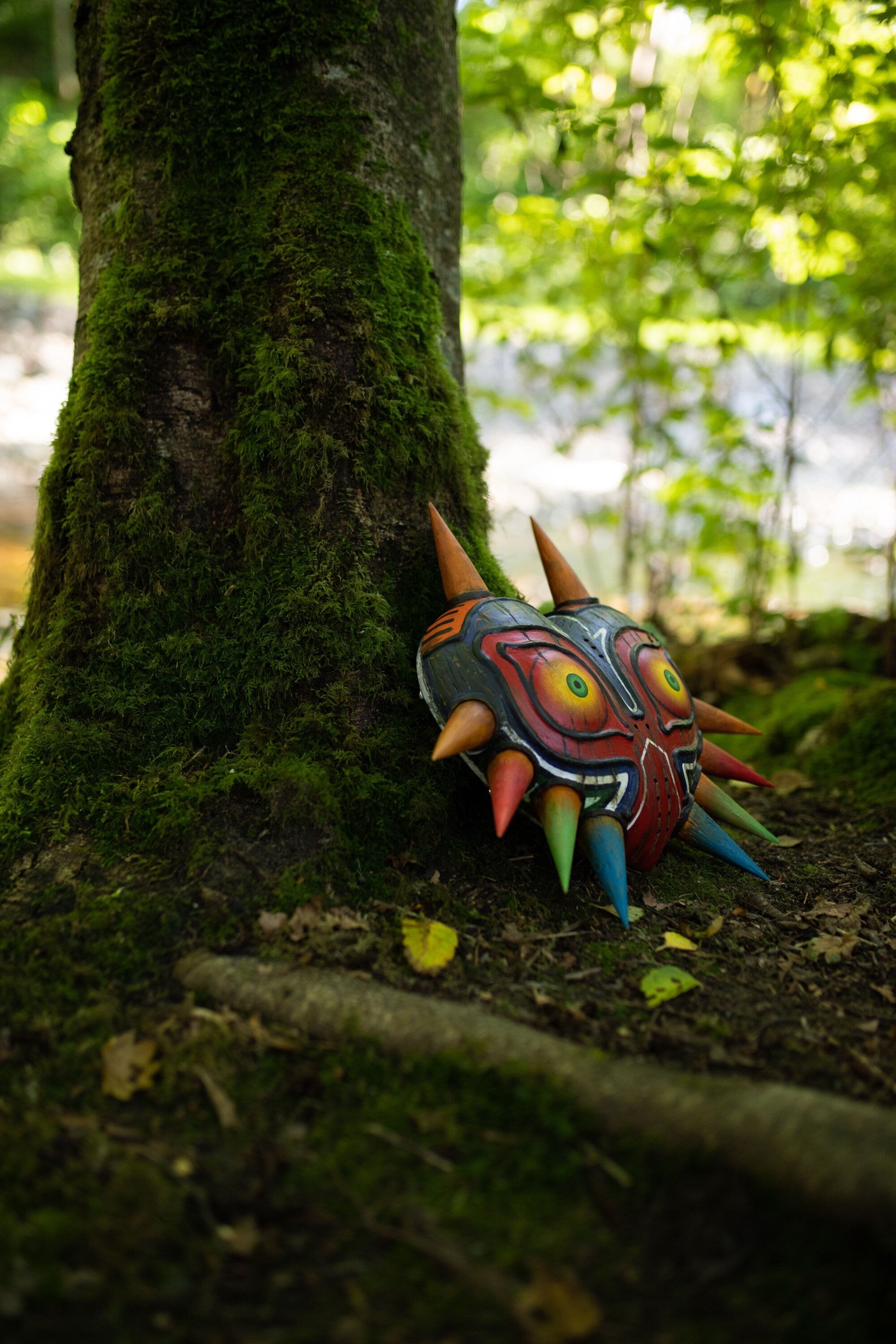 Majora's Mask Wooden Replica Hand Carved // The Legend of Zelda leaning against a tree in forest setting