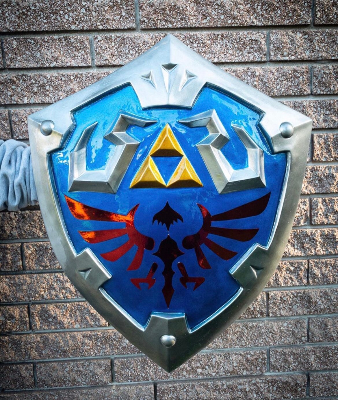 Shield with a prominent Hylian emblem against a brick wall