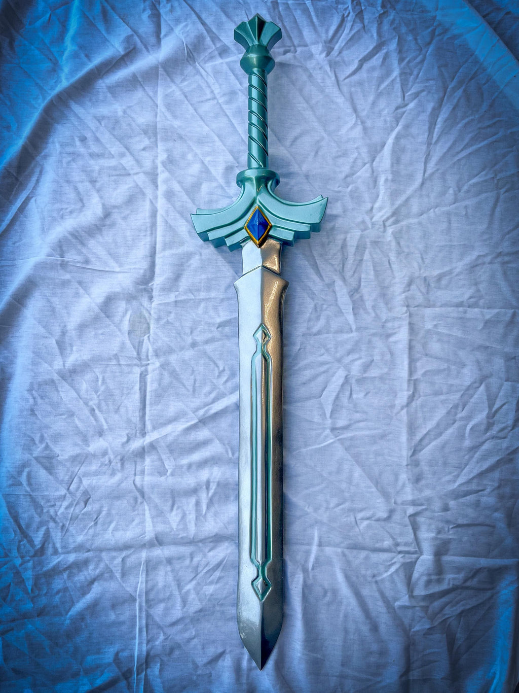 Decorative sword with a blue and gold design on a textured white background