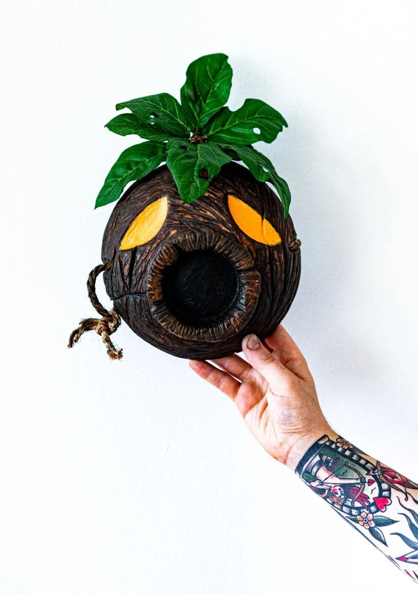Hand holding a decorative Deku Mask object against a white background
