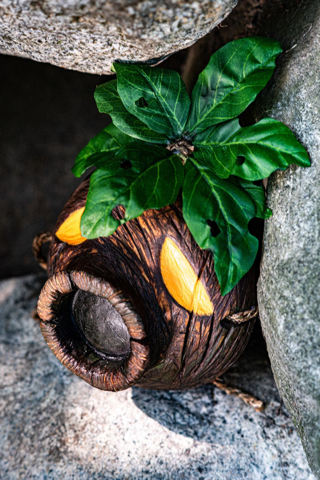 Wooden Deku Mask with leaves against a stone background