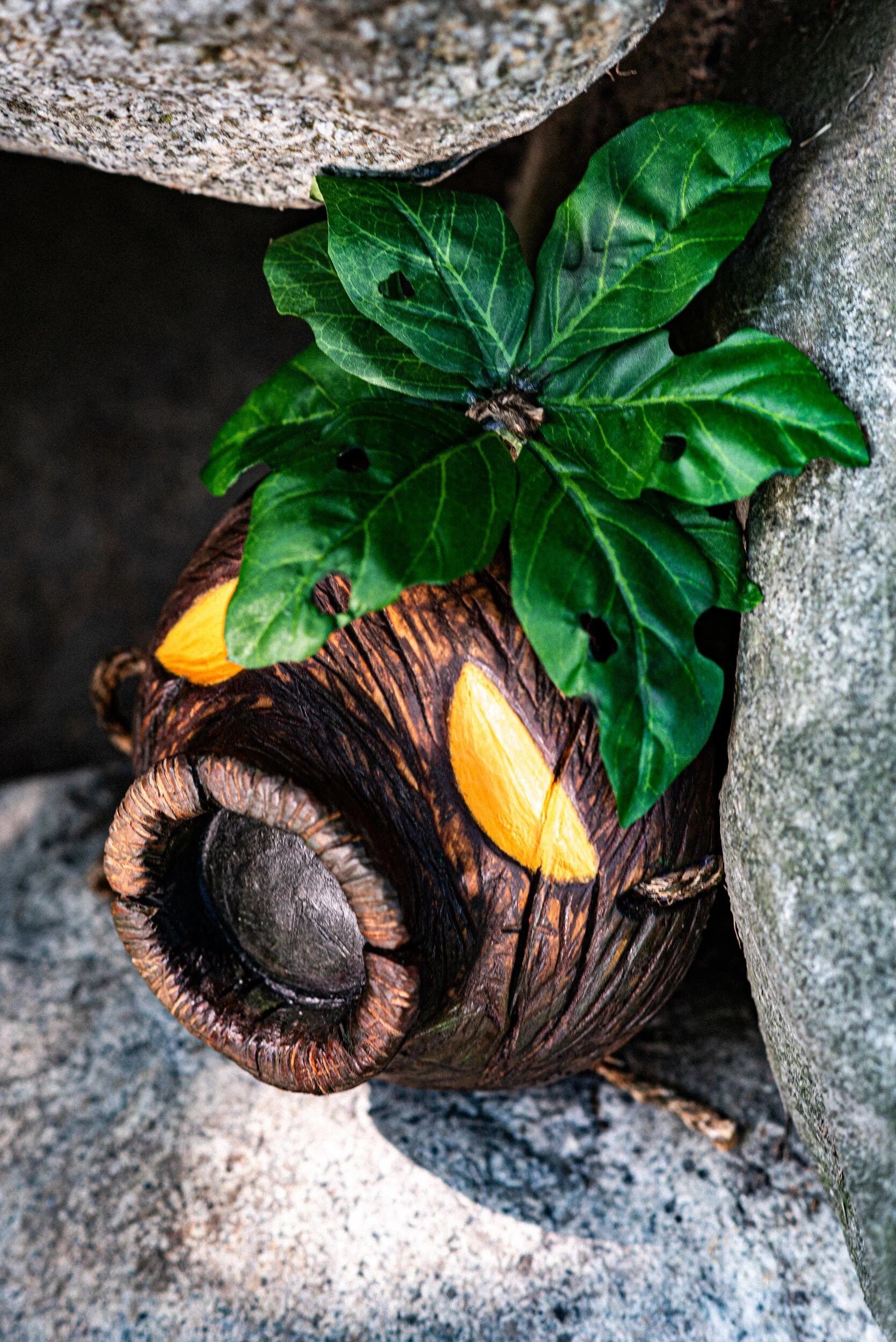 Wooden Deku Mask with leaves against a stone background