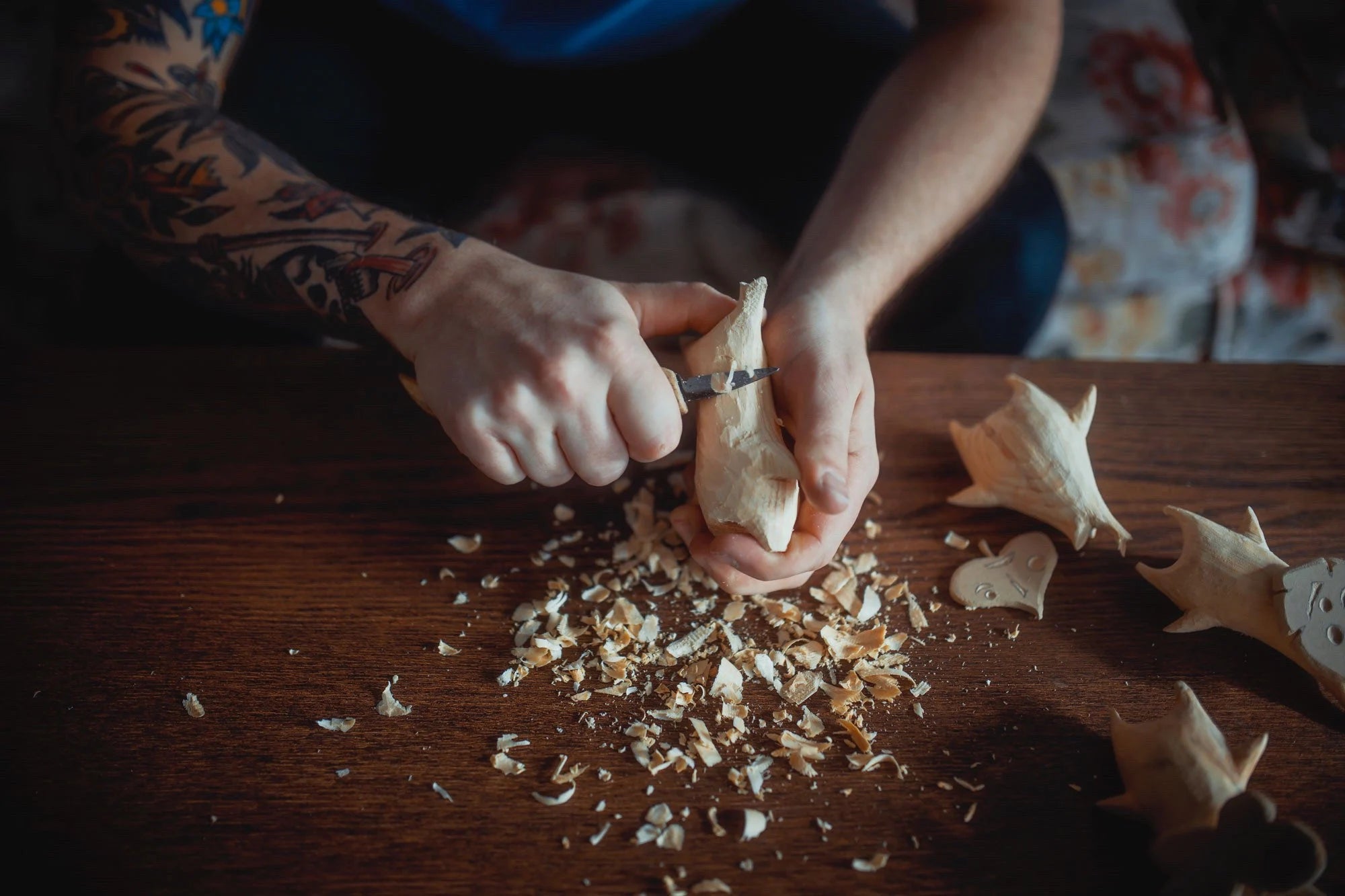 Person carving figurines on a wooden table.