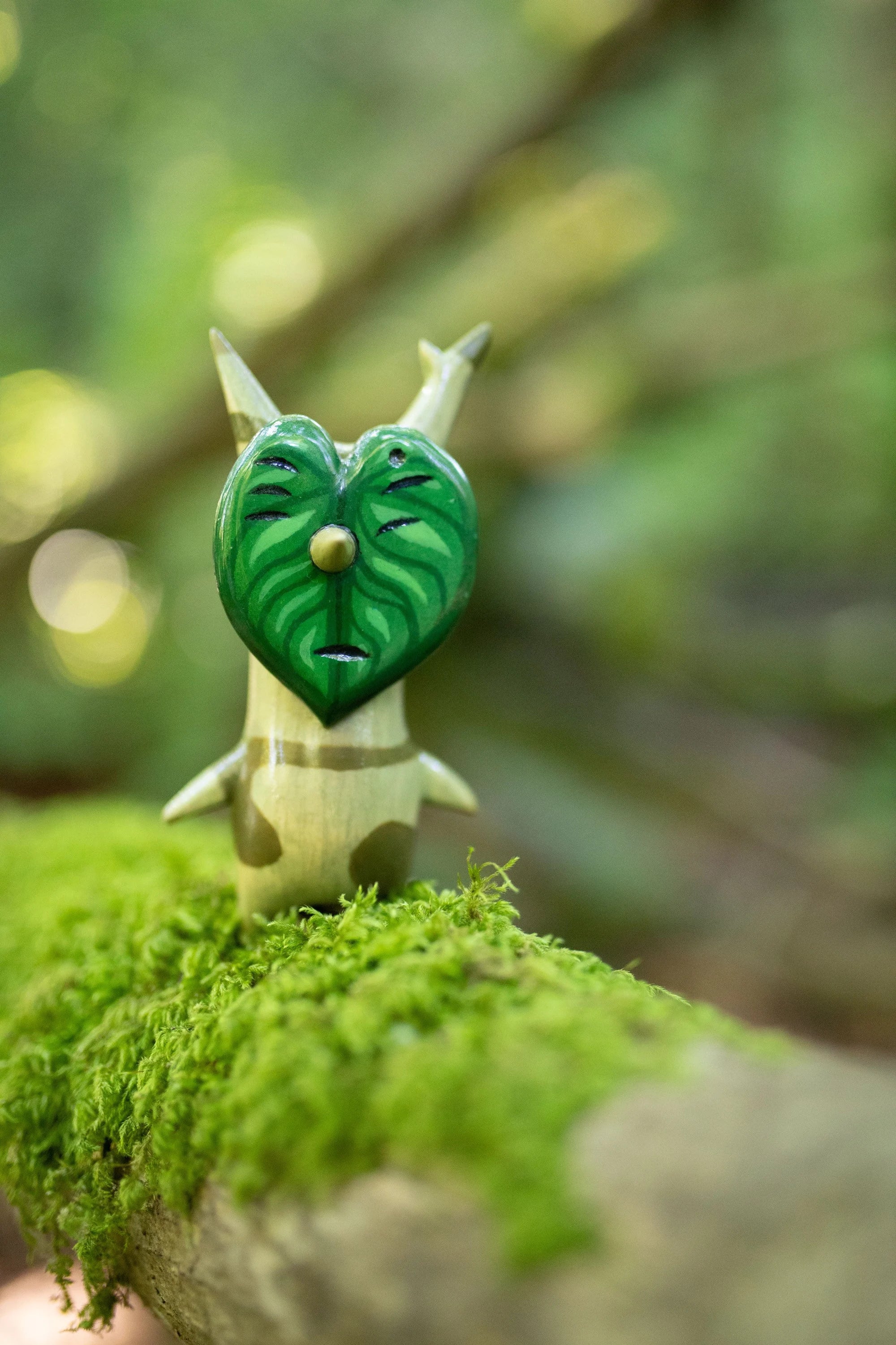 Small figurine with a leaf design on a mossy surface Wooden Korok Statue // Aldo - The Legend of Zelda